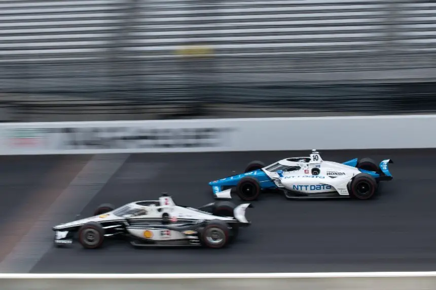 Josef Newgarden and Alex Palou drive down the Indianapolis Motor Speedway front stretch.