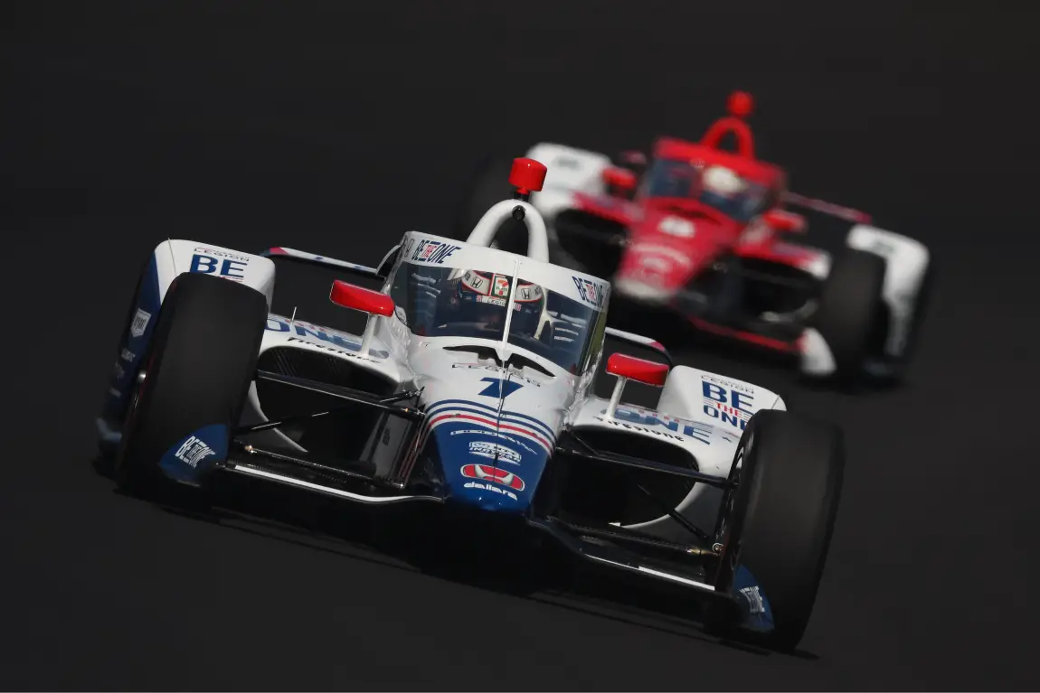 Tony Kanaan and Marcus Ericsson driving around the Indianapolis Motor Speedway.