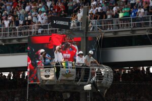 Aaron Likens waves the red flag as members of Marcus Ericsson's crew anguish on the big screen behind Likens during the 2023 Indianapolis 500.