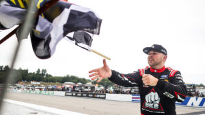 Layne Riggs collects the checkered flag after winning the Team EJP 175 at New Hampshire Motor Speedway