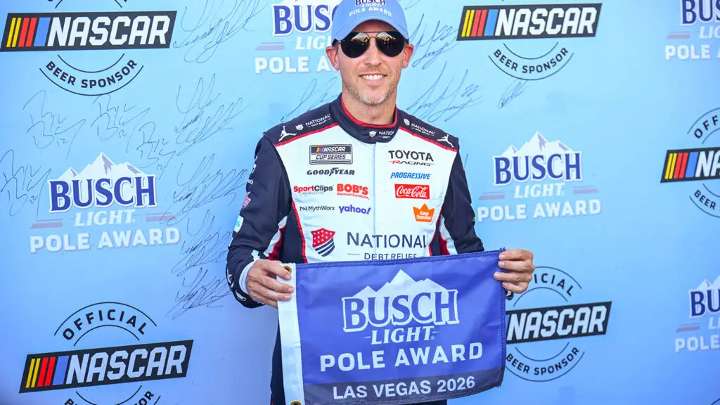Denny Hamlin holds up the pole award flag after winning the pole for the South Point 400 at Las Vegas Motor Speedway.