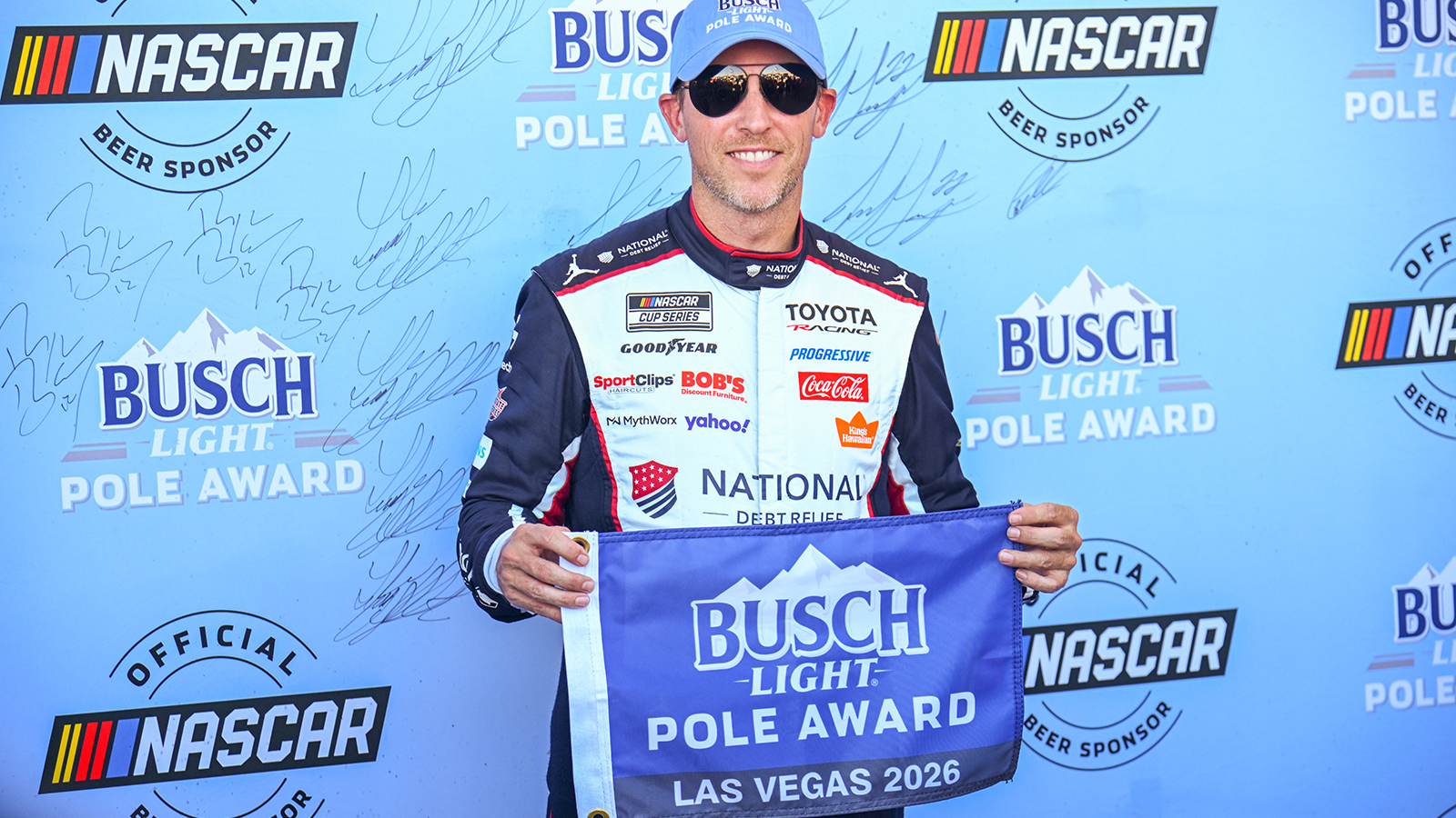 Denny Hamlin holds up the pole award flag after winning the pole for the South Point 400 at Las Vegas Motor Speedway.